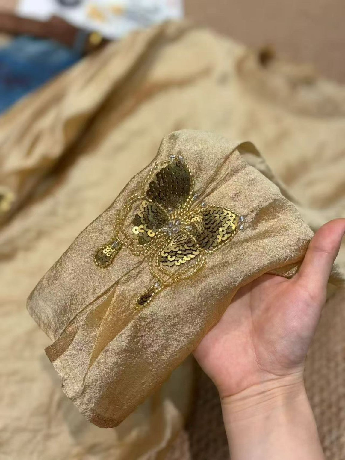 Close-up of butterfly beadwork on the brown blouse cuff
