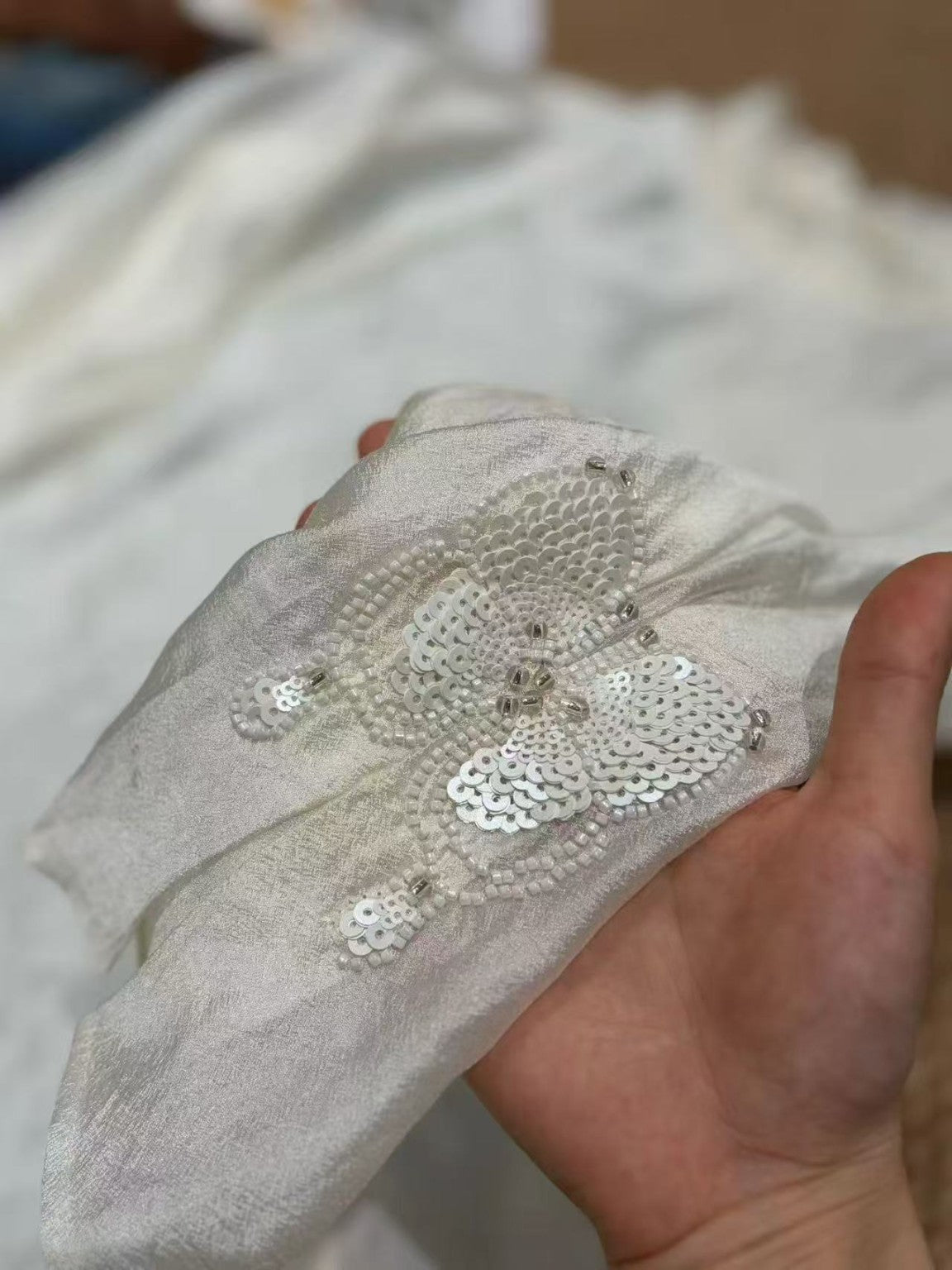 Close-up of butterfly beadwork on the white blouse cuff